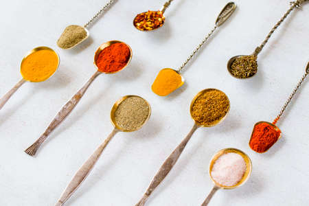 variation of spices on the vintage silver spoons, all spices on the table, colorful food background
