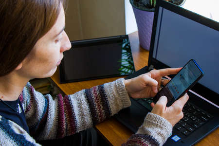 Tbilisi, Georgia - October 09, 2020: Woman working with notebook in workplace, digital tablet, mobile phone, coffee and plants in workspace, home workingの写真素材