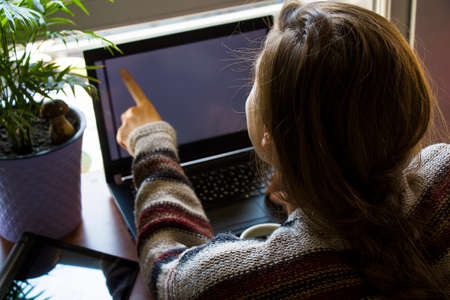 Woman working in office with digital tablet and notebook, writing and typing on the device