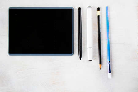 Drawing and painting tablet and styles pen and pencils on the white background, high angle view