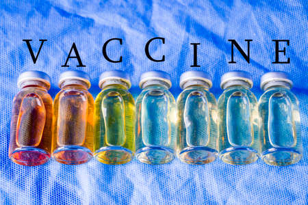 Corona virus and Covid - 19 new vaccine in ampules, different color variations of vaccine on the blue backgroundの写真素材