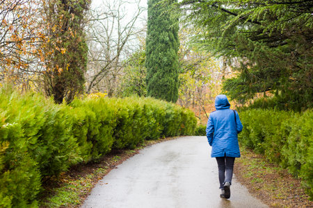 Woman in the botanic garden and park, trees and casual young girl portrait in garden during rainの写真素材