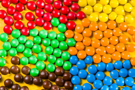 M&M's candy on the yellow background, colorful candy and multicolored gradientの写真素材
