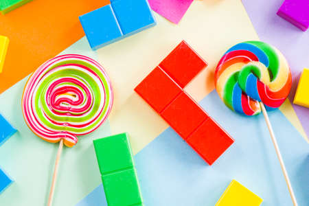 Colorful candies, lollypop and colorful puzzle cubes on the colorful background, candies and toy