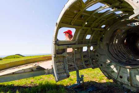 Beautiful women with red hat, sunglasses and suitcase near old and abandoned Soviet union army jetの写真素材