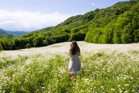 Women with dress in field of daisy flowers during sunlightの写真素材