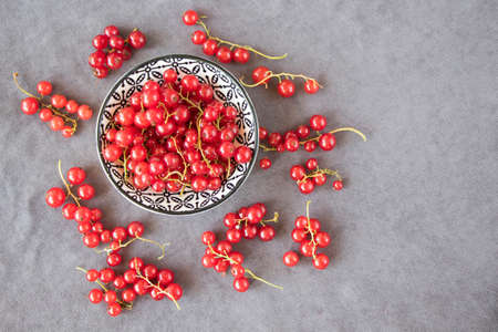 Red currant on the gray cloth background. Large group of colorful berries.