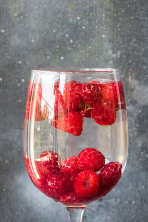 Loganberry the wineglass on the gray and blue background. Large group of colorful berries.の写真素材