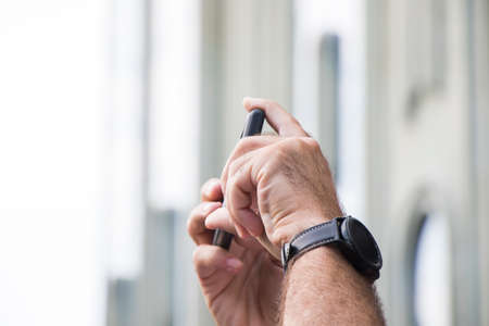 Mobile phone and mans hands with watch