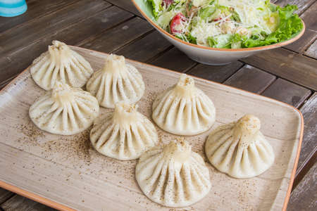 Georgian traditional food khinkali on the plate in restaurant, ready to eat, hot dish on the wooden...