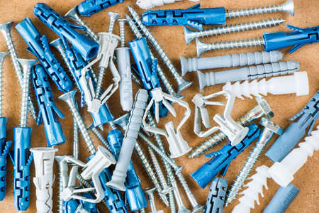 Large group of different wall plugs and screws on the brown background, high angle view