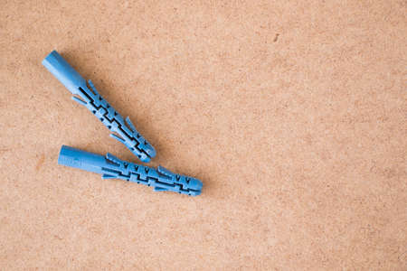 Blue plastic wall plugs on the brown background, high angle view