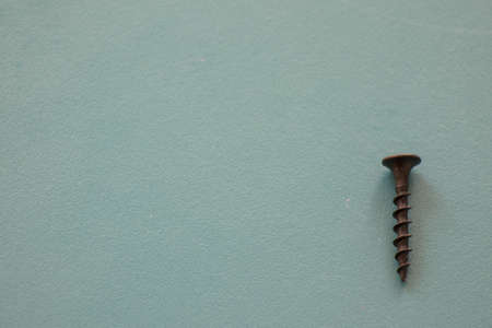 Black threaded screw on the green background, high angle view