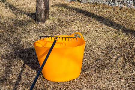 Orange bucket and black rake, gardening equipment and toolの写真素材