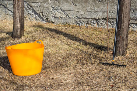 Orange bucket and black rake, gardening equipment and toolの写真素材
