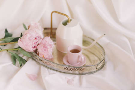 Peonies on a tray with a cup and a teapotの写真素材