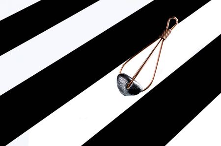 Lead fishing feeder on black and white stripe background