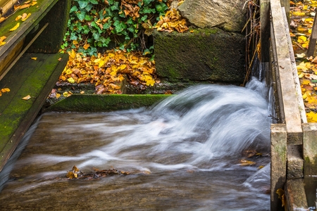Old wooden water mill in the forest at autumn.の写真素材