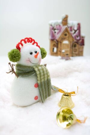 Snowman with bells standing in front of the house.の写真素材