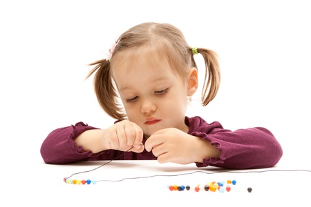 Young little girl beading on isolated white backgroundの写真素材