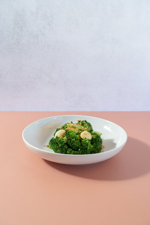 Fried broccoli with garlic on a white plate on a pink backgroundの写真素材