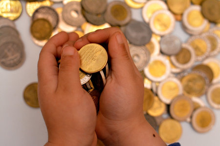A pile of coins in the hand of a child, stack of Egyptian money coins held by a young child, the concept of economy future, collecting money for charity, and saving moneyの写真素材