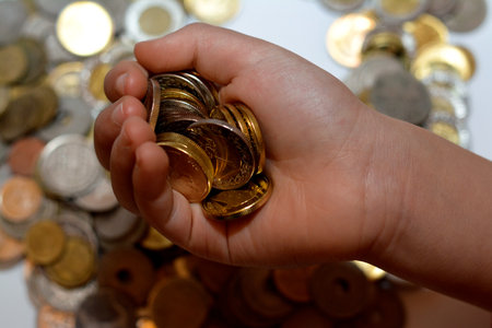 A pile of coins in the hand of a child, stack of Egyptian money coins held by a young child, the concept of economy future, collecting money for charity, and saving moneyの写真素材
