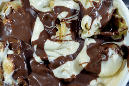 Sweet chocolate mix rolls stuffed with banana fruit pieces, nuts, hazelnuts, raisins, white and brown chocolate sauce with toppings of white and dark chocolate spread chocolate, selective focusの写真素材