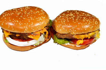 A juicy thick double beef patty with cheese covered with sauce, crispy lettuce, fresh tomatoes, onions and pickles in a large sesame seed bun, a beef burger hamburger sandwich with special saucesの写真素材
