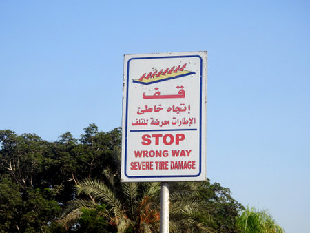 A warning road sign in Arabic and English, Translation of Arabic words ( Stop, Wrong way, Severe Tire Damage ) as a caution before a spikes barrier on the road that will cause Tyre damage  on that wayの写真素材