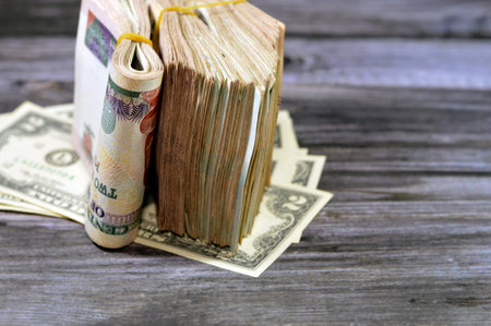 Folded Egyptian money  200 LE and pile of American money isolated on wood, two hundred Egyptian...
