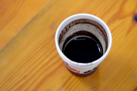 A drunk cup of Turkish coffee in a disposable drinking foam cup isolated on a wooden background, with text of coffee, cup and a train figure, Foam cups are insulated with no heat transferの写真素材