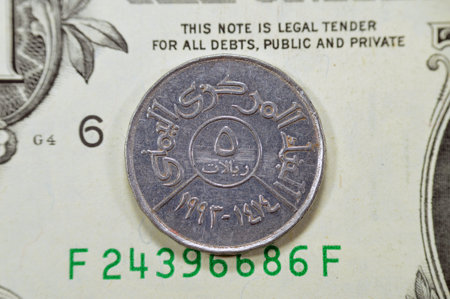 Vintage retro old 5 Yemeni riyals coin with value, date, and the central bank of Yemen building, on a USD dollars banknote, United States of America money, Yemeni American exchange rates, old coinの写真素材