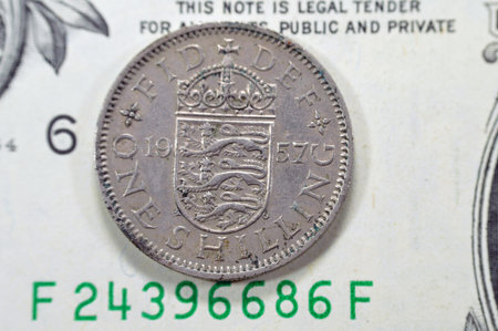Reverse side of 1 one shilling Elizabeth II 1957 features Crowned English shield of arms dividing...