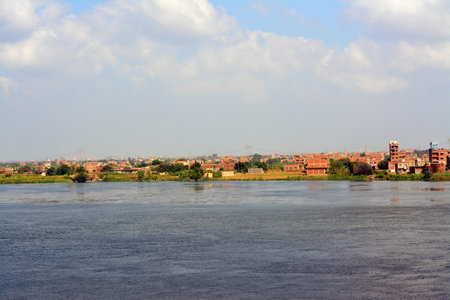 Giza, Egypt, September 9 2022: The Nile river in Egypt, with a village buildings in Giza on its coast, The Nile is a major north-flowing river in northeastern Africa, flows into the Mediterranean Seaの写真素材