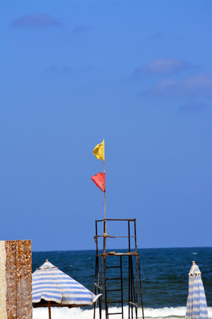 Yellow and red flags on the beach, beach warning flag system, red flag means High risk, rough conditions, strong surf, and currents, Yellow flag means Medium risk, light surf currents, lifeguardの写真素材