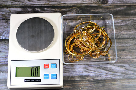Pile stack of gold and a digital accurate scale in grams, bracelets, rings and gold chains, gold price concept, precious metal, savings, selling, buying and purchasing precious metal of goldの写真素材
