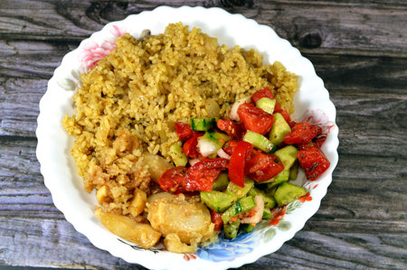 Egyptian rice cooked on hot steam, green salad and fried squid, a mollusc with an elongated soft body, large eyes, eight arms, and two tentacles in the superorder Decapodiformes, selective focusの写真素材