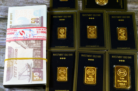 Cairo, Egypt, December 8 2023: 24K karat BTC Bullion Trading Center pure yellow gold of bars and sovereign coin, and a stack of Egyptian money banknote 50 EGP LE pounds, gold price buying and sellingのeditorial素材