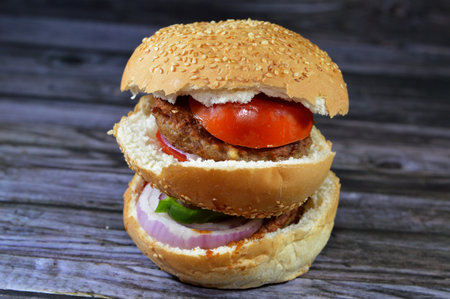 spicy fried beef burger cooked in a boiling shallow oil with slices of  tomatoes, onions, bell peppers in burger bun topped with sesame seeds, Fast food, Junk food concept, beef meat burger sandwichの写真素材