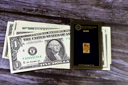 Cairo, Egypt, January 2 2024: American dollars and 24K karat BTC Bullion Trading Center pure yellow gold 1 gram bar, gold investment, exchange price rate, inflation crisis and saving money assetsのeditorial素材