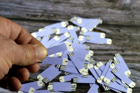 test strips for diabetic patients that measures random blood sugar (blood glucose) at home isolated on wooden background, test strip to measure blood sugar level with a drop of the patient bloodの写真素材