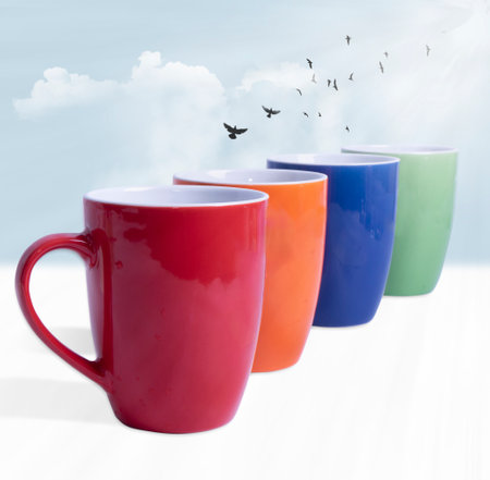 Mugs of tea in different colors. With interesting light and clouds and birdsの写真素材