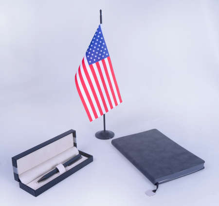 USA Desktop flag and gray plain velveteen notebook and gray pen metal in a beautiful box. On White backgroundの写真素材