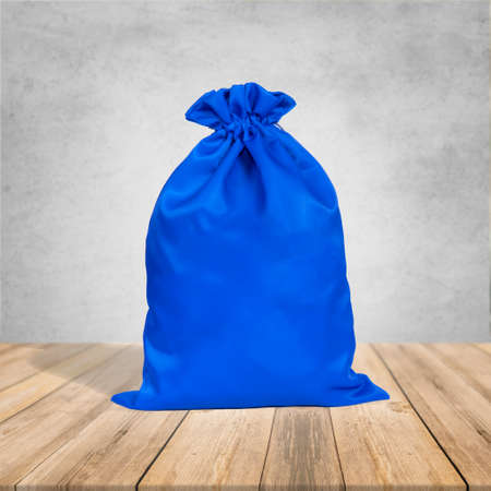 blue Burlap bag with Drawstring canvas. On wooden desk and gray wall colorの写真素材