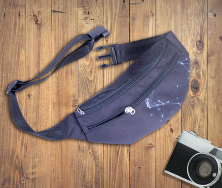 Black Fanny Pack for Men and Women - Waist Bag, Belt Bag, Waist Pack with zippers on wooden desk and camera.の写真素材