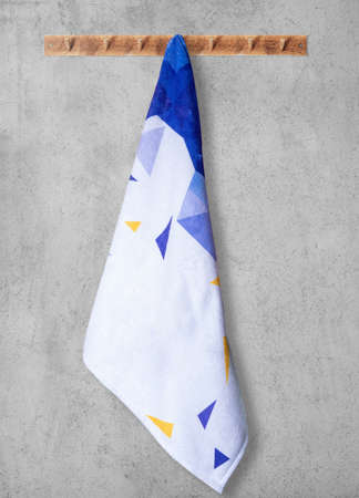 White towel with an abstract design on a wooden hanger. On a gray wall.の写真素材