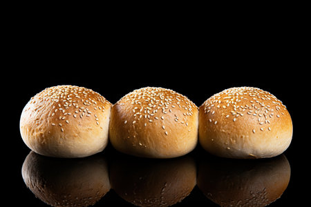 Three buns with sesame seeds on a black background with reflectionの素材