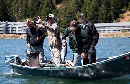 Gold Beach, Oregon, August 14, 2010:  Four young men show off their catch to a passing boat at the mouth of the Rogue River.のeditorial素材