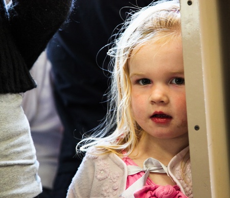 London, England, June 19, 2010: A curious but shy young girl peeks around an entrance way on a London train.のeditorial素材